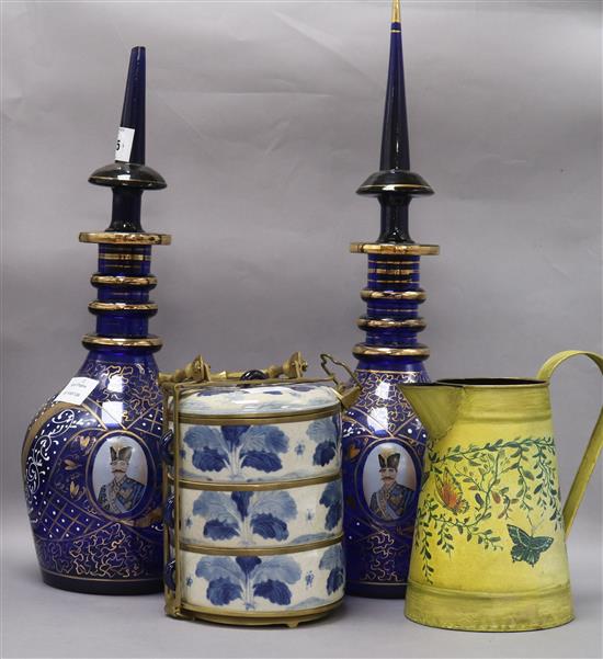 A pair of Egyptian dark blue glass decanters and stoppers, a Chinese blue and white metal mounted stacking box and a toleware jug talle
